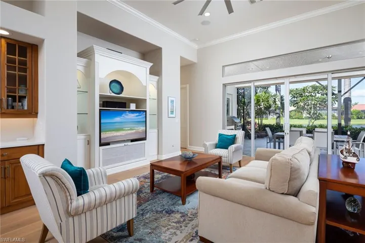 Living area with ornamental molding, wood finished floors, a ceiling fan, built in features, and recessed lighting