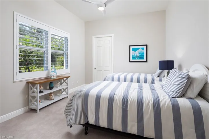 Bedroom with light colored carpet and a ceiling fan