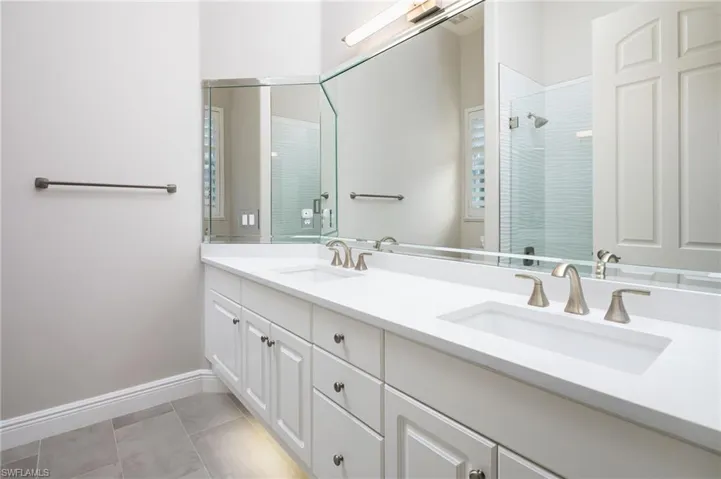 Full bathroom featuring a tile shower, double vanity, and light tile patterned flooring