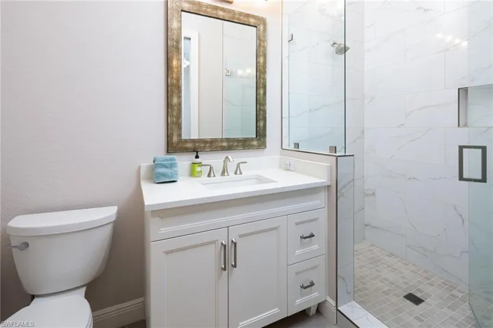 Bathroom featuring a marble finish shower, vanity, and a textured wall