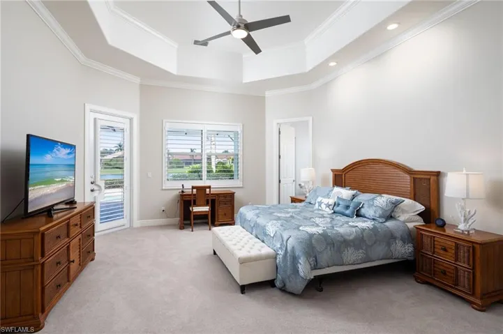 Bedroom featuring access to exterior, a tray ceiling, a ceiling fan, carpet, and ornamental molding