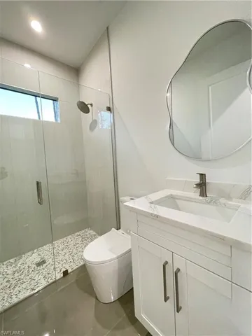 Bathroom with a shower with shower door, toilet, and vanity