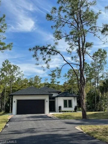 View of front facade featuring a garage and a front lawn