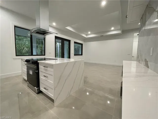 Kitchen featuring stainless steel electric range oven, white cabinets, a center island, french doors, and light stone countertops