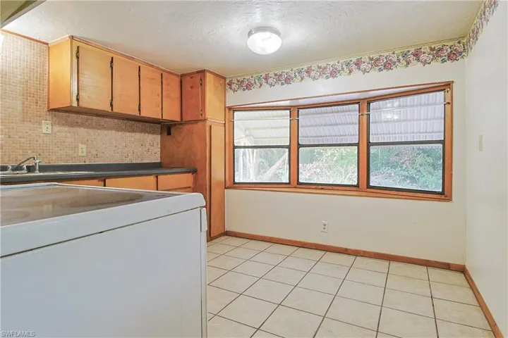 Laundry room featuring light tile patterned flooring and a textured ceiling