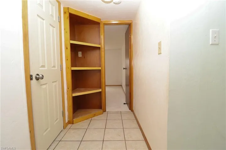Hallway with light tile patterned floors and baseboards