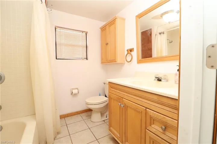 Full bathroom featuring light tile patterned floors, vanity, and shower / bath combo with shower curtain