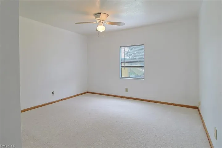 Carpeted spare room featuring baseboards and ceiling fan