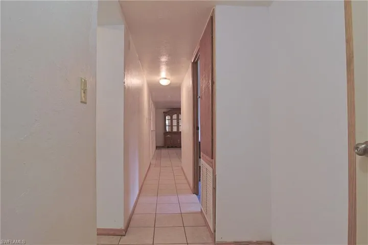 Hall with light tile patterned floors and a textured wall