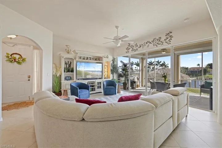 Living area featuring a ceiling fan, light tile patterned flooring, and arched walkways