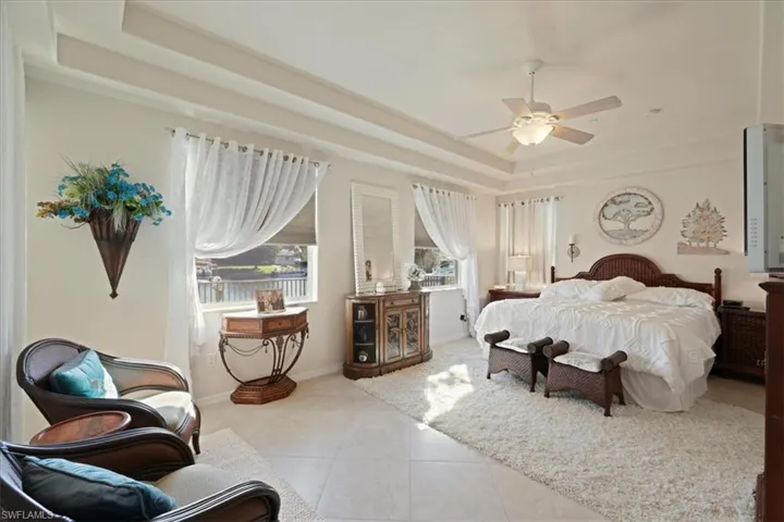 Bedroom featuring a tray ceiling, ceiling fan, and tile patterned floors
