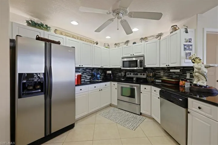 Kitchen featuring stainless steel appliances, white cabinetry, decorative backsplash, recessed lighting, and ceiling fan