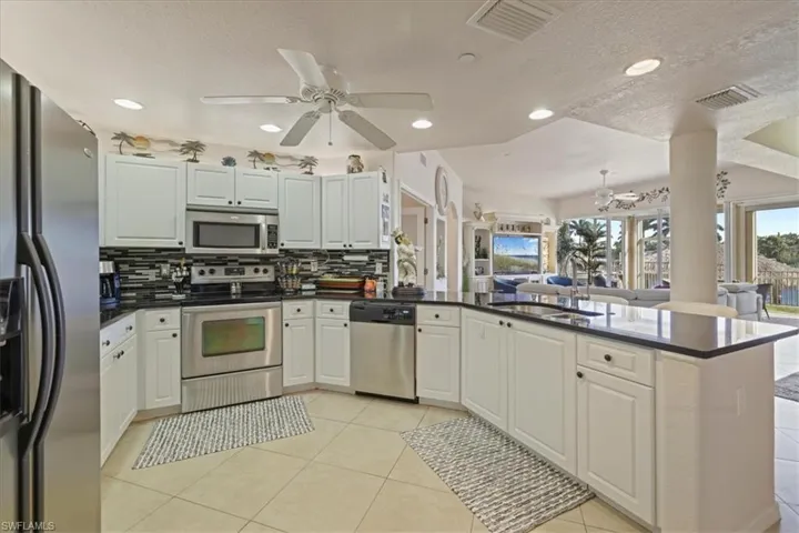 Kitchen with stainless steel appliances, open floor plan, a ceiling fan, tasteful backsplash, and recessed lighting