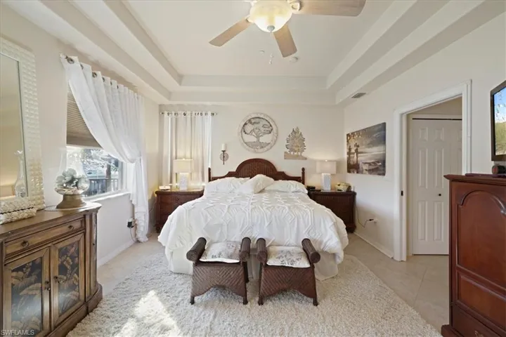 Bedroom featuring a ceiling fan, a tray ceiling, and light tile patterned flooring