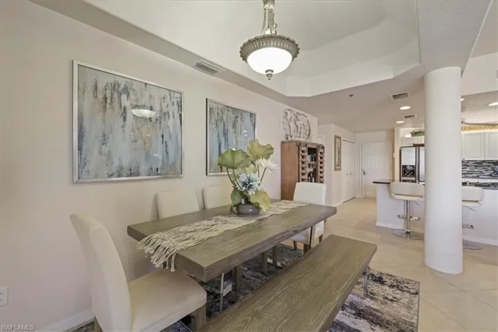 Dining room with a raised ceiling, light tile patterned flooring, and recessed lighting