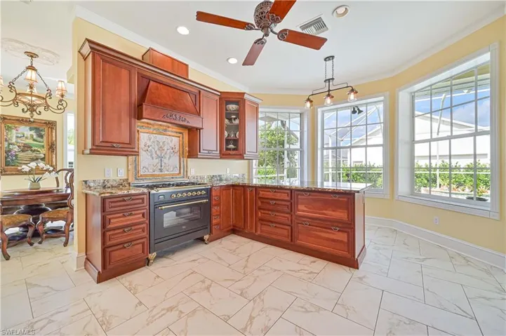 Kitchen featuring light tile patterned flooring, high quality range, hanging light fixtures, and premium range hood