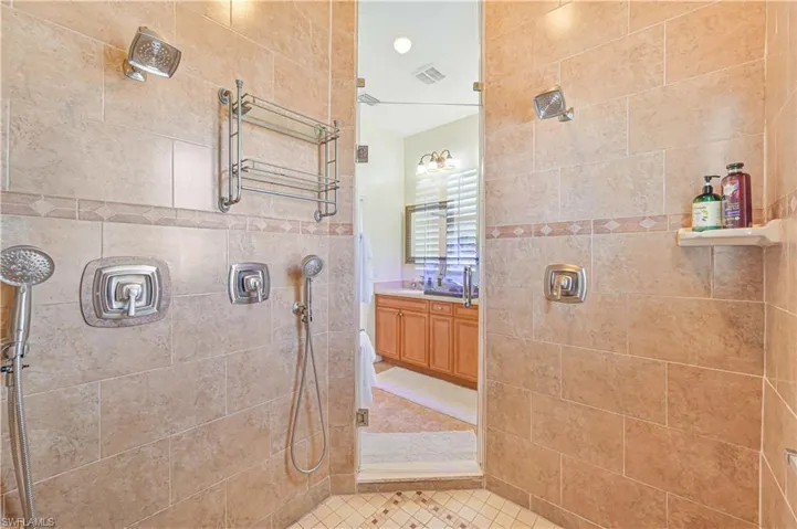 Bathroom featuring tiled shower and vanity