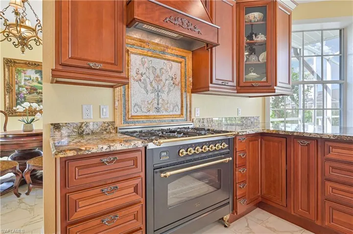 Kitchen featuring light tile patterned flooring, custom exhaust hood, light stone counters, and designer stove