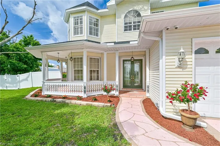 Entrance to property with a garage, a yard, and covered porch