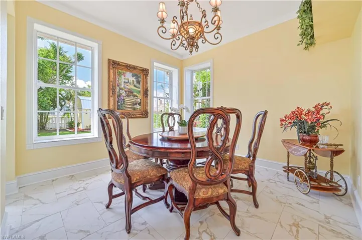 Tiled dining room with an inviting chandelier, crown molding, and a wealth of natural light