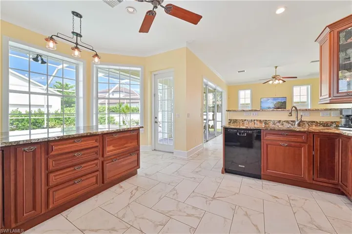 Kitchen with decorative light fixtures, ceiling fan, sink, dishwasher, and light tile patterned floors