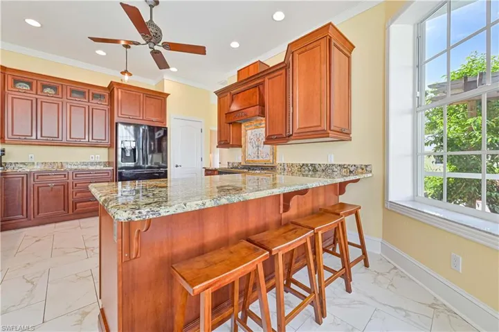 Kitchen featuring light tile patterned flooring, black refrigerator with ice dispenser, a wealth of natural light, and ceiling fan