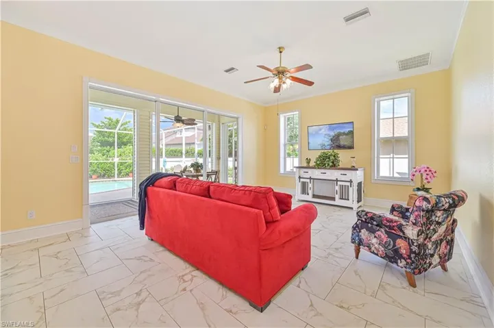 Living room with ceiling fan, ornamental molding, and light tile patterned floors