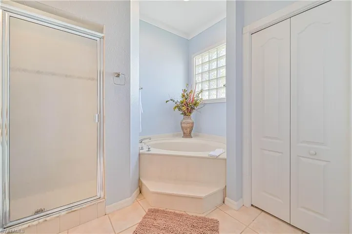 Bathroom with separate shower and tub, tile patterned floors, and crown molding