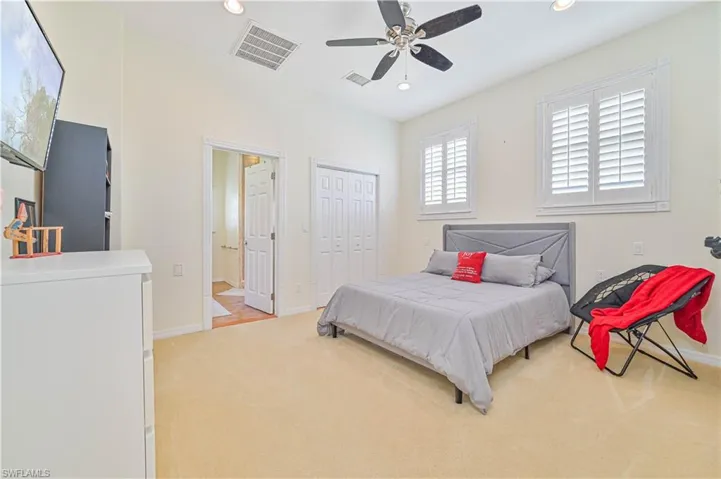 Bedroom featuring a closet, light colored carpet, and ceiling fan