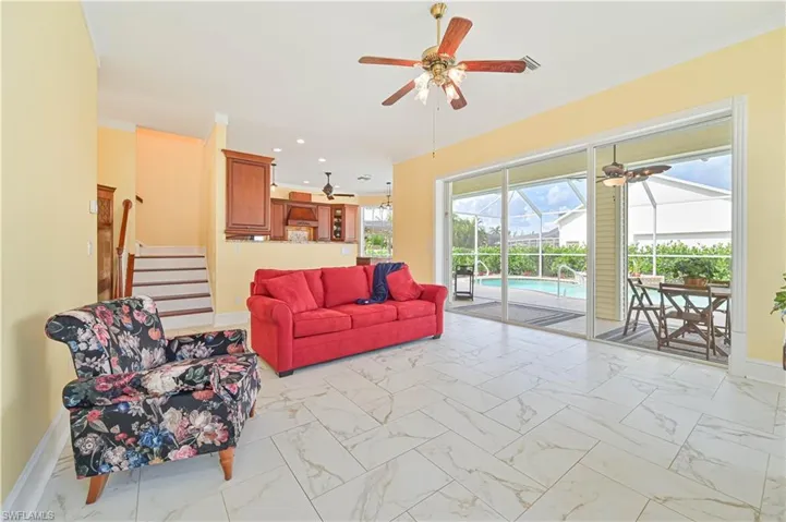 Tiled living room with ceiling fan and ornamental molding