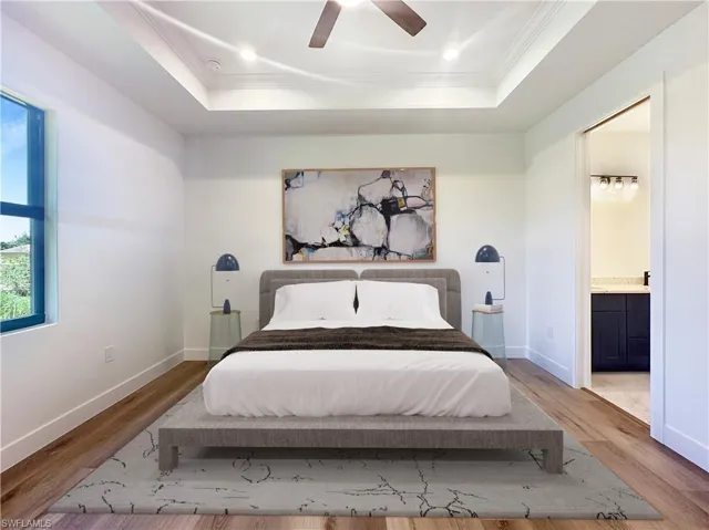 Bedroom with ceiling fan, ornamental molding, hardwood / wood-style floors, a tray ceiling, and ensuite bathroom. Virtually staged