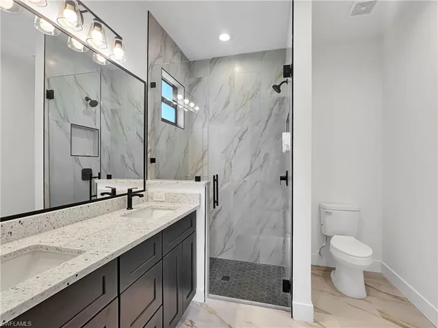 Bathroom with toilet, vanity, a shower with door, and tile patterned floors