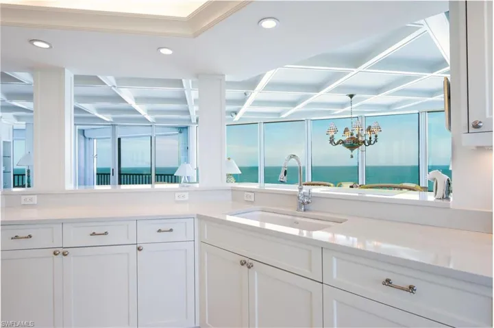 Kitchen with white cabinetry, light stone counters, a chandelier, and a water view