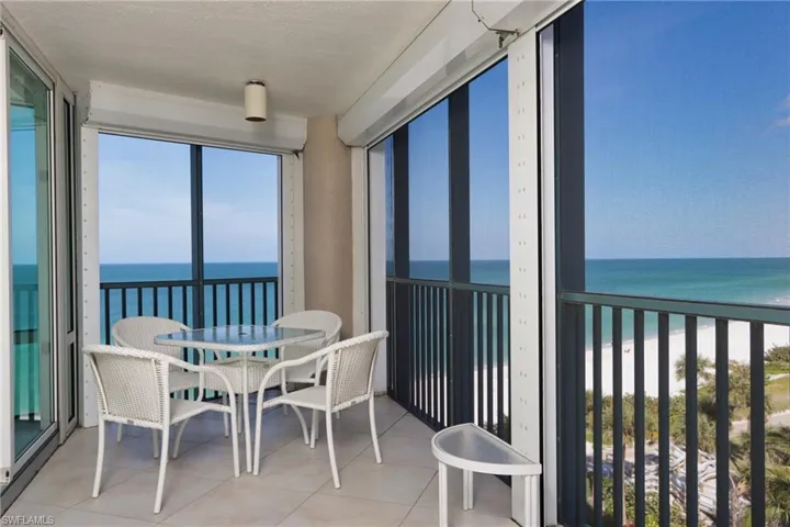Sunroom with view of water and beach