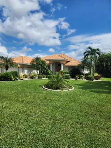 View of front of home with a tile roof, a front yard, and stucco siding