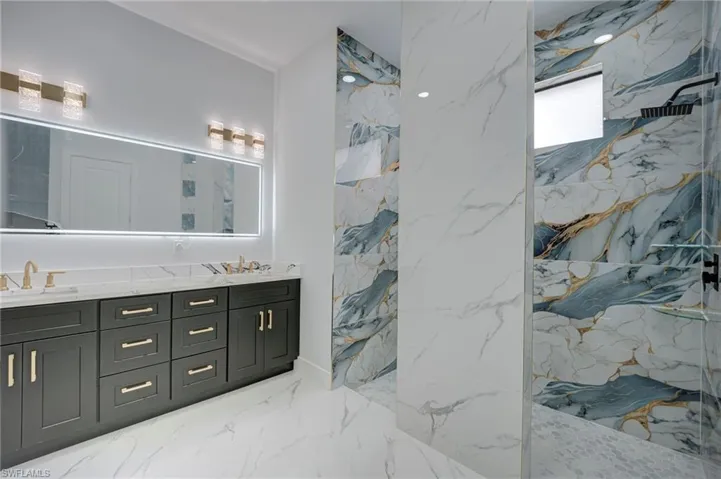 Full bath with a marble finish shower and double vanity