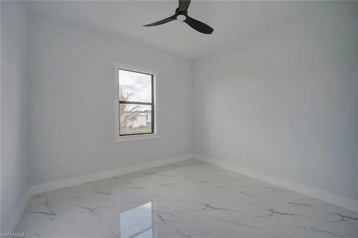 Empty room featuring light marble finish flooring and a ceiling fan