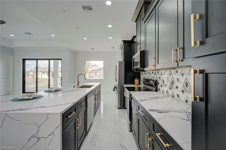 Kitchen featuring light stone counters, stainless steel appliances, a large island, recessed lighting, and decorative backsplash