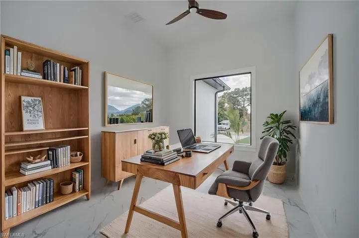 Office space with light marble finish floors and a ceiling fan