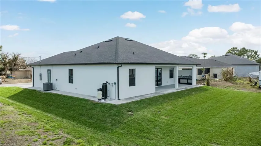 Back of house with a patio, stucco siding, a yard, and roof with shingles