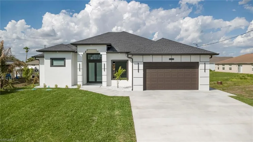 View of front facade with a garage, a front yard, roof with shingles, and driveway
