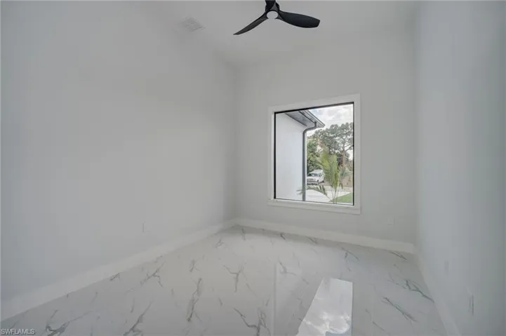 Empty room featuring light marble finish flooring and ceiling fan