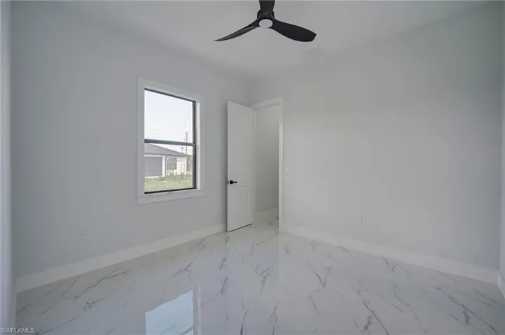 Unfurnished room featuring light marble finish flooring and a ceiling fan