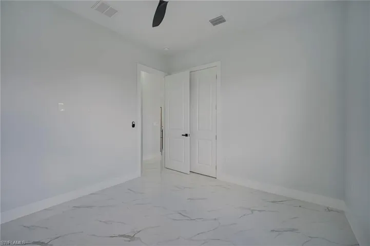 Empty room featuring light marble finish flooring and a ceiling fan