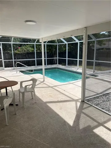 View of swimming pool with glass enclosure, a patio area, a fenced backyard, and a fenced in pool