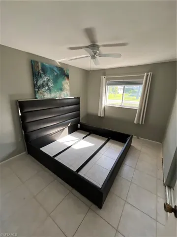 Bedroom with light tile patterned floors, ceiling fan, and baseboards