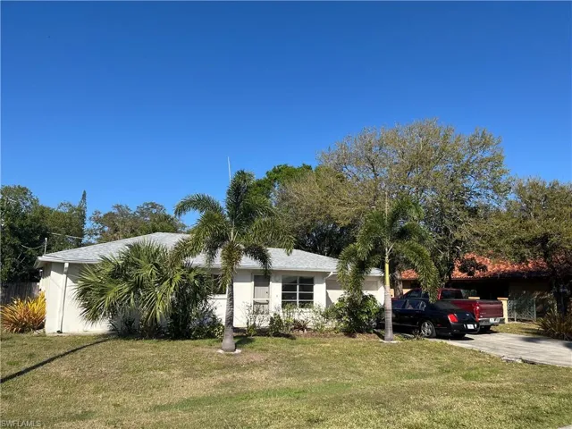 View of front of home with an attached garage, concrete driveway, a front yard, and stucco siding