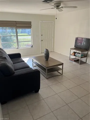 Living room featuring light tile patterned flooring, a ceiling fan, and baseboards