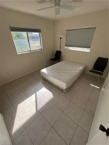 Unfurnished bedroom featuring ceiling fan, baseboards, and tile patterned floors
