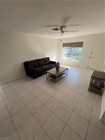 Unfurnished living room with a ceiling fan, visible vents, baseboards, and light tile patterned floors